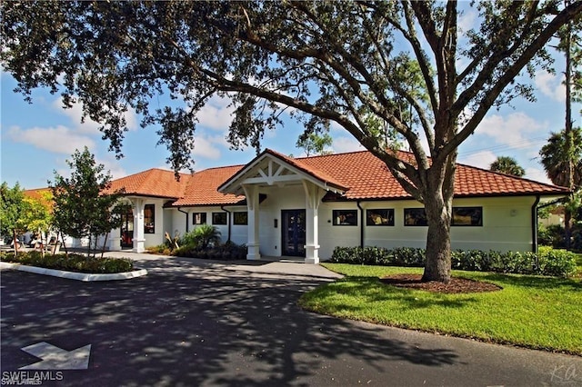 view of front of house featuring driveway, a tiled roof, and a front lawn