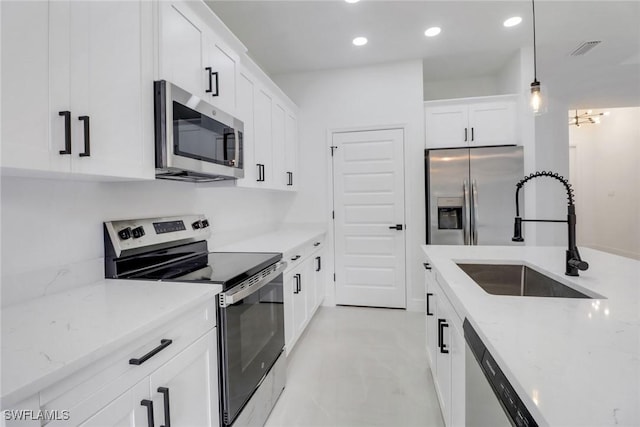 kitchen featuring pendant lighting, sink, white cabinets, light stone counters, and stainless steel appliances