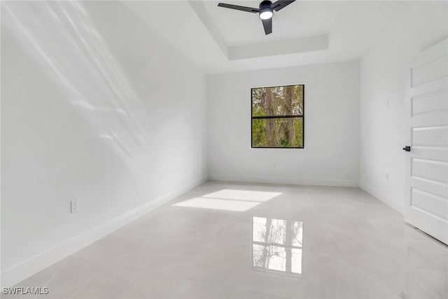 unfurnished room with ceiling fan and a tray ceiling