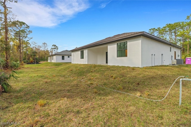 back of property featuring a yard and central AC