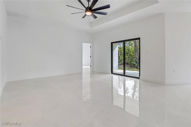 spare room featuring a raised ceiling and ceiling fan