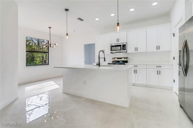 kitchen featuring a kitchen island with sink, pendant lighting, white cabinetry, and appliances with stainless steel finishes