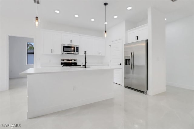 kitchen featuring pendant lighting, white cabinetry, a center island with sink, and appliances with stainless steel finishes