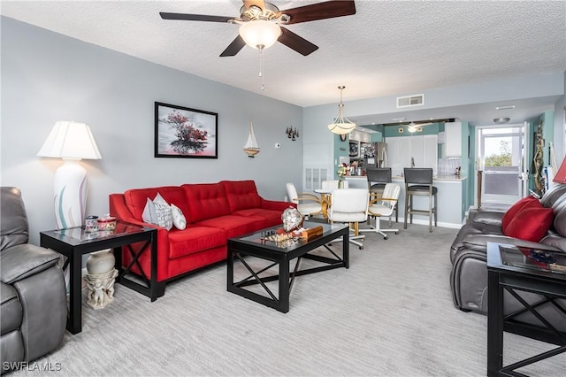 carpeted living room featuring ceiling fan and a textured ceiling