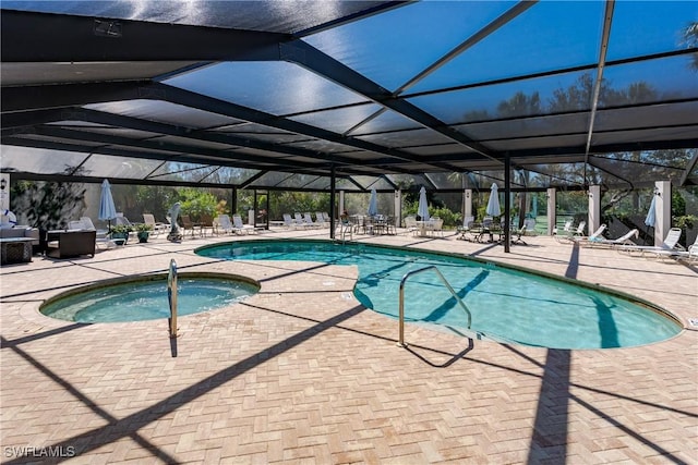 view of pool with glass enclosure, an in ground hot tub, and a patio area