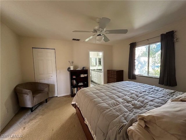 bedroom with light carpet, ceiling fan, and ensuite bath