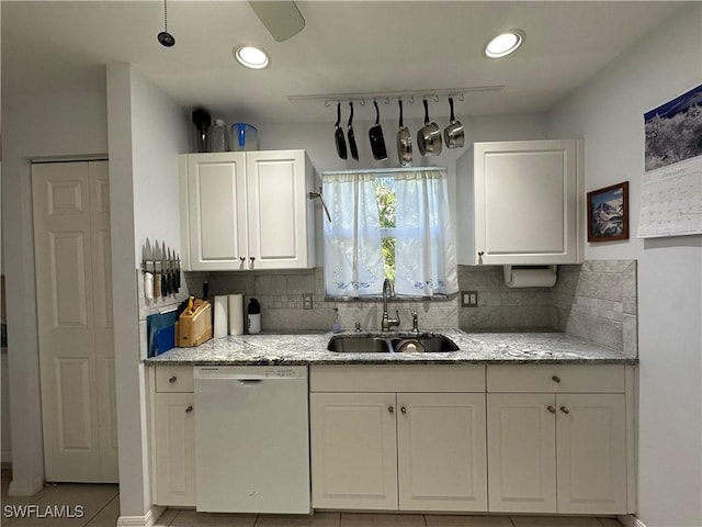 kitchen with white cabinetry, sink, dishwashing machine, and light stone counters