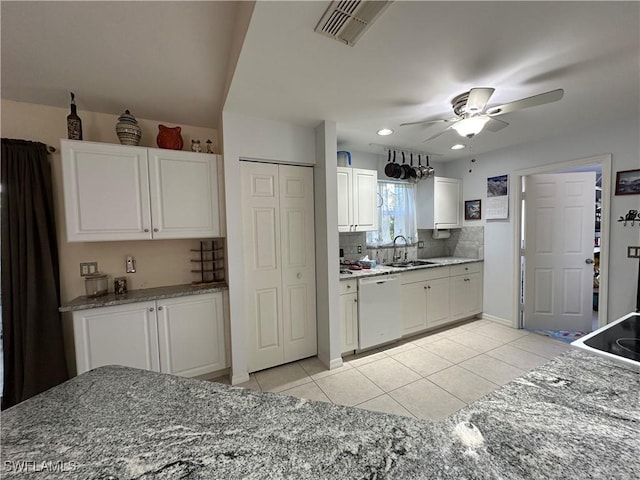 kitchen featuring sink, light tile patterned floors, dishwasher, white cabinetry, and decorative backsplash