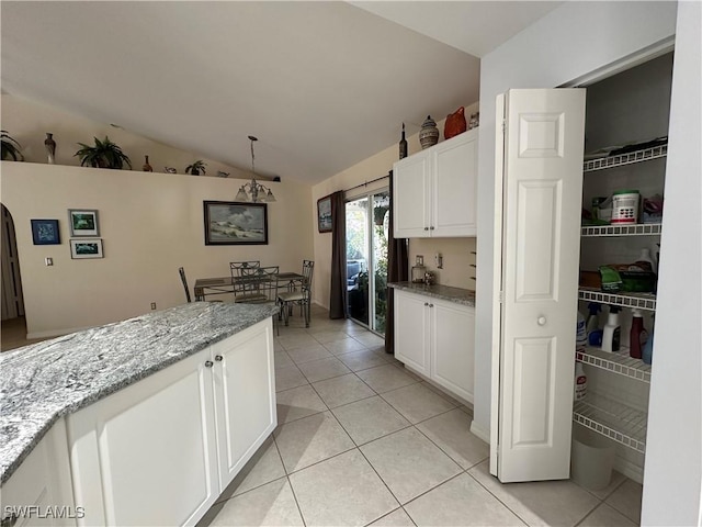 kitchen featuring white cabinetry, light tile patterned floors, light stone counters, and lofted ceiling