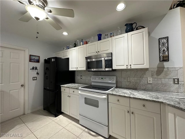 kitchen featuring black refrigerator, white range with electric stovetop, white cabinets, light tile patterned floors, and light stone countertops