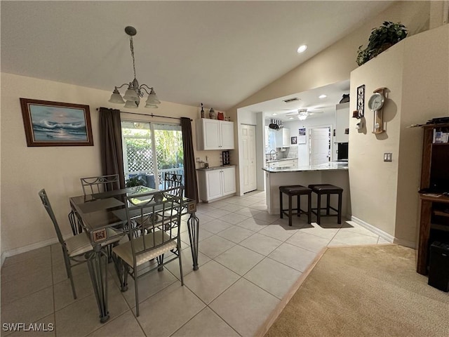 dining room with ceiling fan with notable chandelier, lofted ceiling, and light tile patterned floors