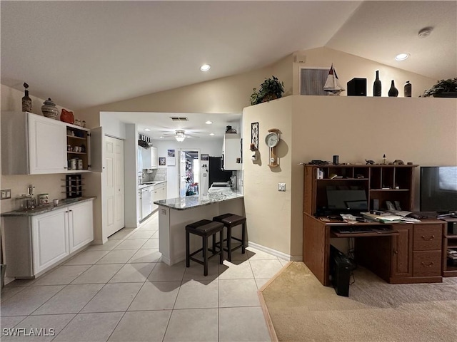 kitchen featuring a kitchen breakfast bar, light stone counters, white cabinets, vaulted ceiling, and kitchen peninsula