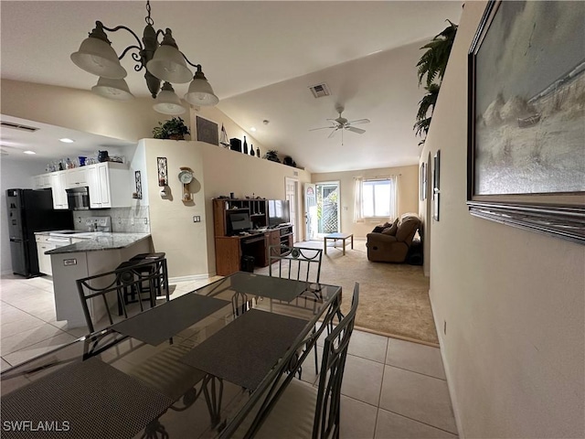 tiled dining room featuring ceiling fan with notable chandelier and vaulted ceiling