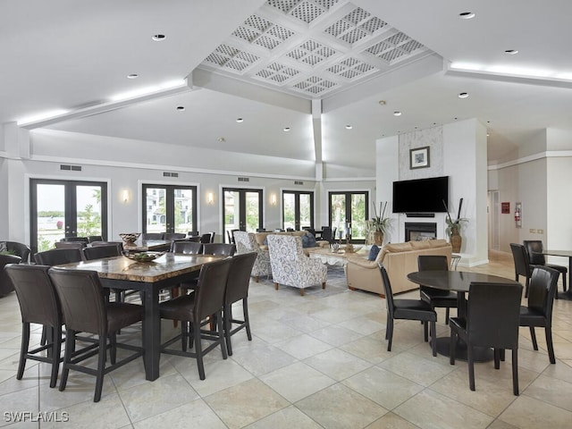 dining room with light tile patterned floors, a large fireplace, french doors, and a towering ceiling