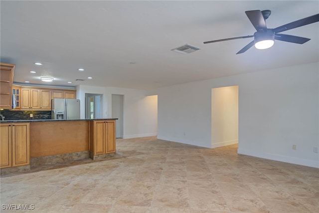 kitchen featuring visible vents, baseboards, stainless steel fridge with ice dispenser, decorative backsplash, and glass insert cabinets