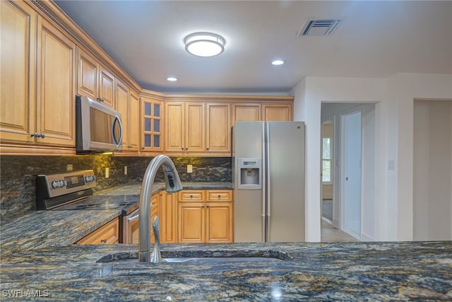 kitchen with glass insert cabinets, visible vents, appliances with stainless steel finishes, and dark stone counters