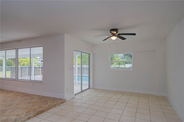 spare room with ceiling fan, baseboards, and light tile patterned flooring