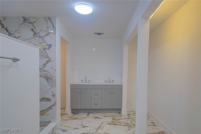 full bath with marble finish floor, visible vents, a sink, and double vanity