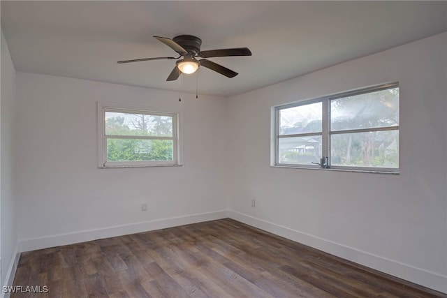 spare room with dark wood-style floors, baseboards, and a ceiling fan