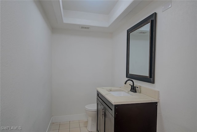 half bathroom featuring baseboards, toilet, tile patterned floors, a tray ceiling, and vanity