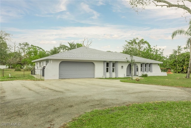 single story home featuring an attached garage, fence, driveway, stucco siding, and a front lawn