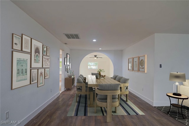 dining area featuring arched walkways, dark wood finished floors, visible vents, and baseboards