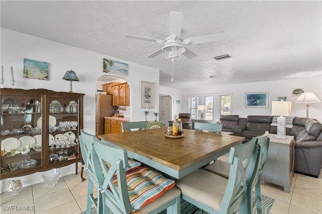 tiled dining room with ceiling fan and a textured ceiling