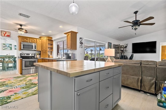 kitchen featuring lofted ceiling, wooden counters, gray cabinetry, stainless steel appliances, and a kitchen island