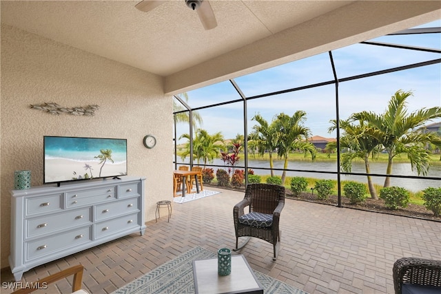 sunroom with a water view and ceiling fan