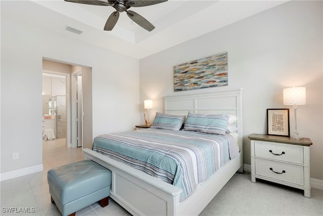 bedroom featuring light tile patterned flooring, ceiling fan, ensuite bathroom, and a tray ceiling