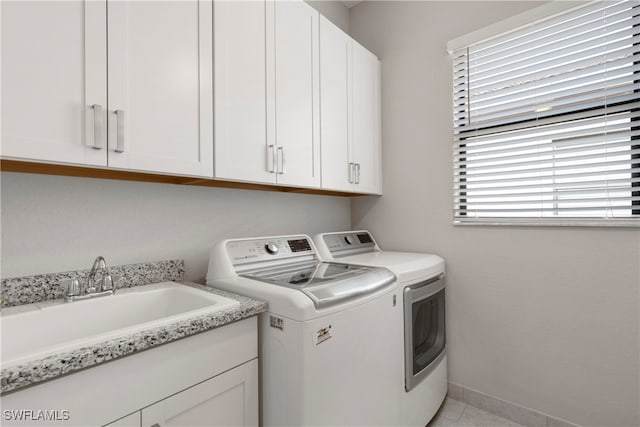 laundry room featuring cabinets, a healthy amount of sunlight, sink, and independent washer and dryer