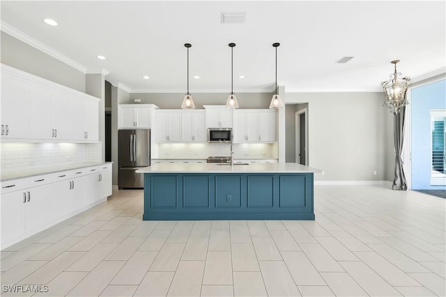 kitchen with backsplash, white cabinetry, decorative light fixtures, stainless steel appliances, and an island with sink