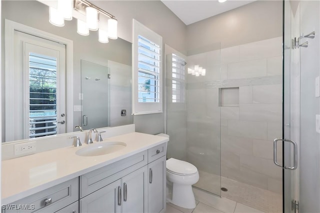 bathroom featuring vanity, a shower with door, toilet, and tile patterned floors