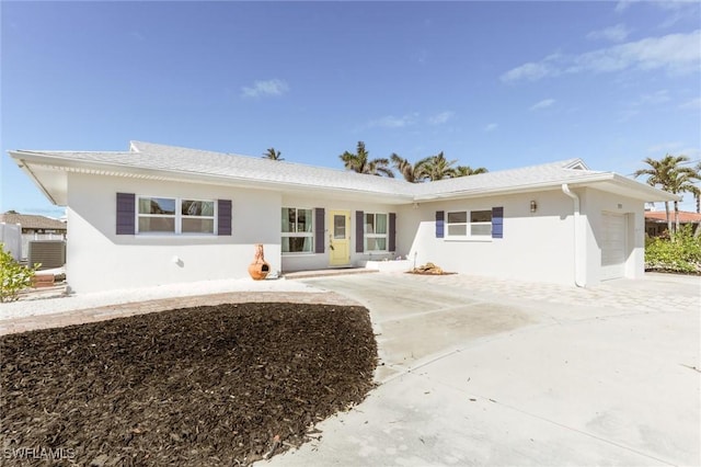 rear view of house featuring a garage, driveway, and stucco siding