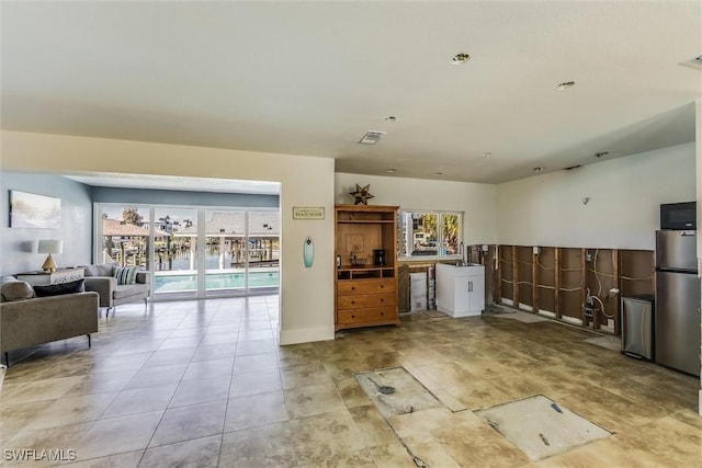 kitchen featuring freestanding refrigerator, open floor plan, light tile patterned flooring, and visible vents