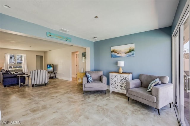 living area with a healthy amount of sunlight, visible vents, and baseboards