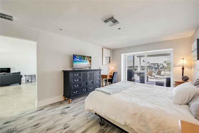 bedroom featuring access to exterior, light wood-type flooring, visible vents, and baseboards