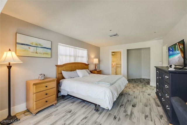 bedroom featuring visible vents, ensuite bath, and light wood-style flooring