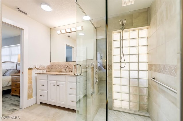 full bathroom with visible vents, connected bathroom, vanity, a shower stall, and tile walls