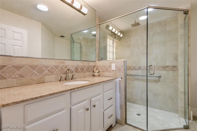 full bath featuring a stall shower, tasteful backsplash, and vanity