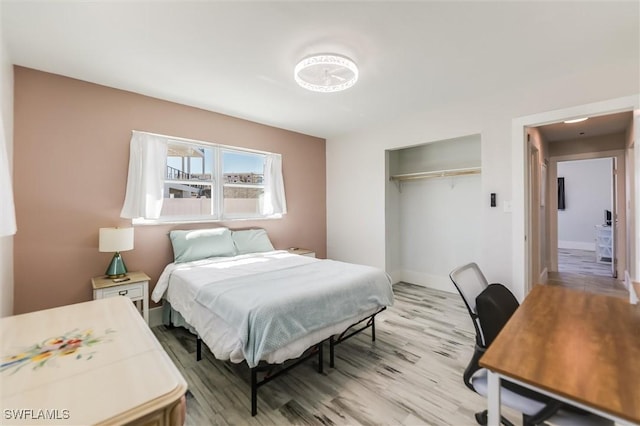 bedroom featuring light wood finished floors, a closet, and baseboards