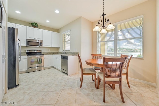 kitchen featuring white cabinets, pendant lighting, light tile patterned floors, and appliances with stainless steel finishes