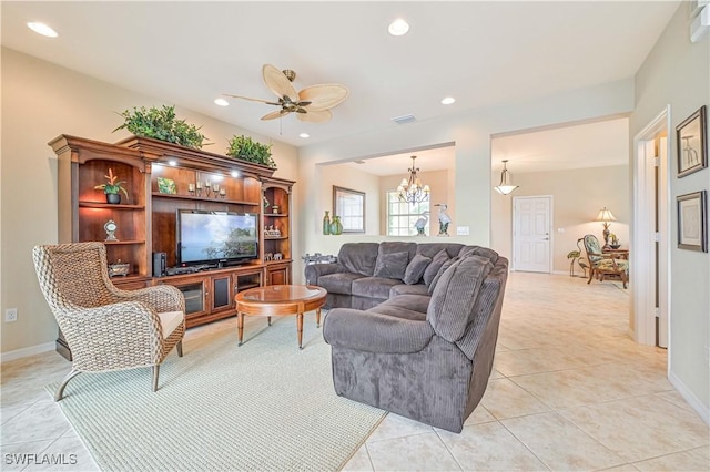 tiled living room with ceiling fan with notable chandelier