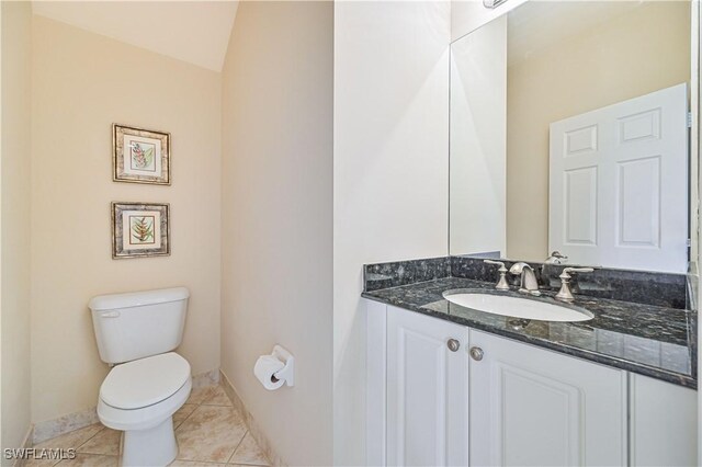 bathroom featuring tile patterned floors, vanity, toilet, and vaulted ceiling