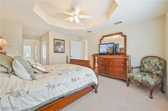 bedroom with light carpet, ceiling fan, and a raised ceiling