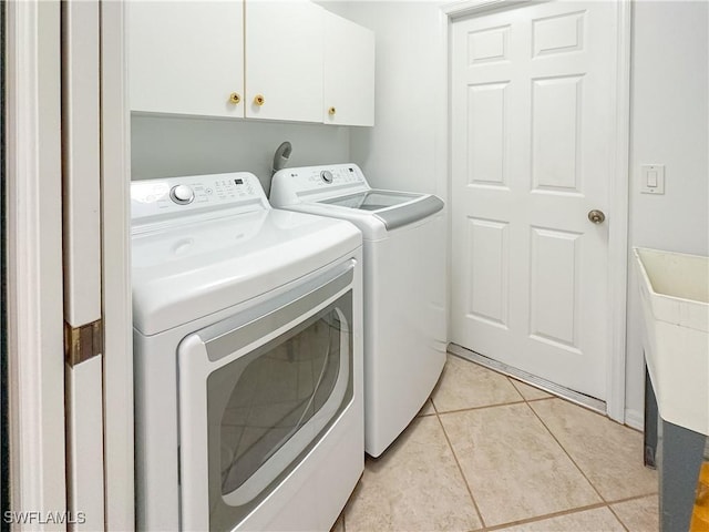 2910 2nd St NE, Naples, FL 34120 - laundry area with washing machine and dryer, cabinet space, and light tile patterned floors