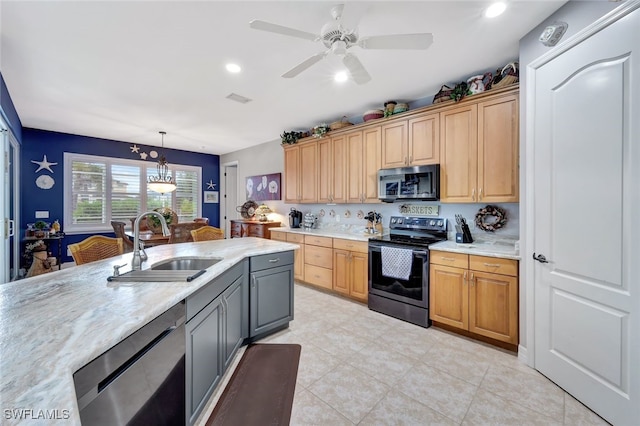 kitchen featuring light stone countertops, decorative light fixtures, stainless steel appliances, sink, and gray cabinets