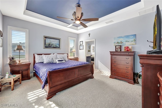 carpeted bedroom featuring ceiling fan, connected bathroom, crown molding, and a raised ceiling