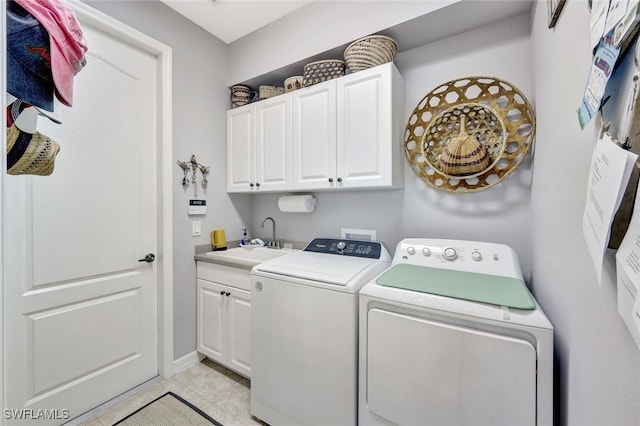 clothes washing area with sink, washing machine and clothes dryer, light tile patterned floors, and cabinets