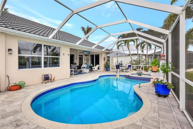 view of swimming pool with glass enclosure, a patio, and ceiling fan